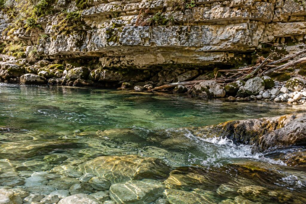 Strates de calcaire horizontal sculptées par une rivière claire coulant sur des galets