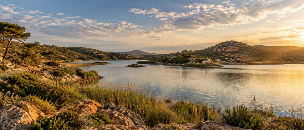 Etendue d'eau calme bordee de collines basses et de garrigue sous un ciel pommele